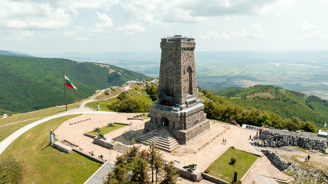 Aerial view Shipka Liberty Memorial monument Bulgaria. Historic stone tower mountain peak summer day. Stara Planina mountains clouds sky background. Bulgarian national landmark drone photography scene