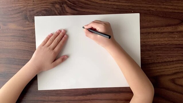 Child writing number three on A4 paper with black pen in slow motion, top view, no sound