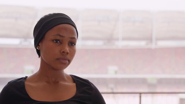 Concentrated female sportswoman during training. Closeup of woman assessing athletic form carefully. Athletic woman maintaining focus on form and breath during practice session in empty stadium