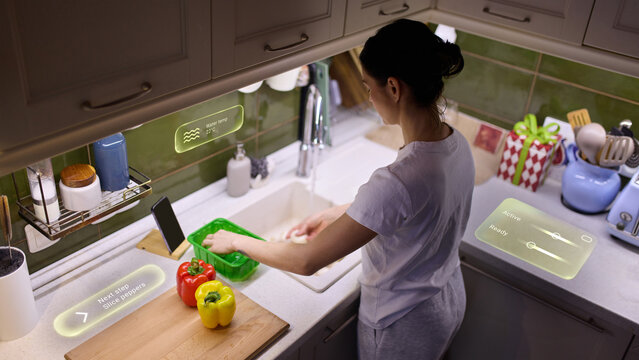 Woman preparing vegetables with smart kitchen guidance interface. Concept of connected home cooking, digital assistant support, step by step guidance and intelligent meal preparation.