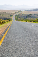 Endless road to horizon through fields and mountains
