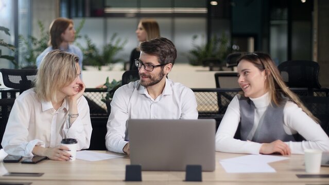 Three people are sitting at a table with a laptop in front of them