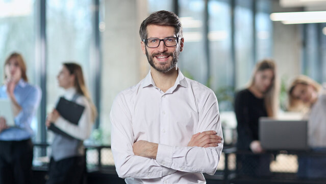 A man in a white shirt is smiling and standing in front of a group of people