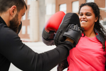 Curvy african american girl and her personal trainer doing boxing sport outdoor - Sport, diet and...