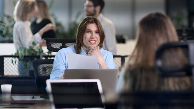 A man is sitting at a desk with a laptop and a piece of paper