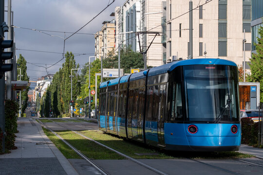 Blue tram on tracks in daylight with modern buildings along an urban street in Oslo Barcode district Norway