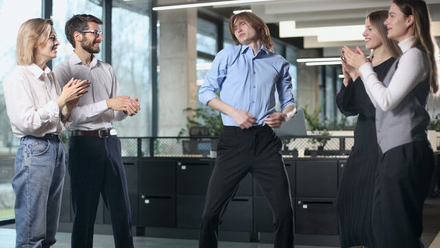 A group of people are standing in a room, one of them is dancing