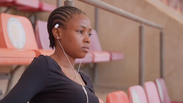 Focused woman readies for competition. Selfassured sportswoman on bleachers gets ready to compete. An assured and focused woman athlete waits patiently on sidelines for her turn to perform