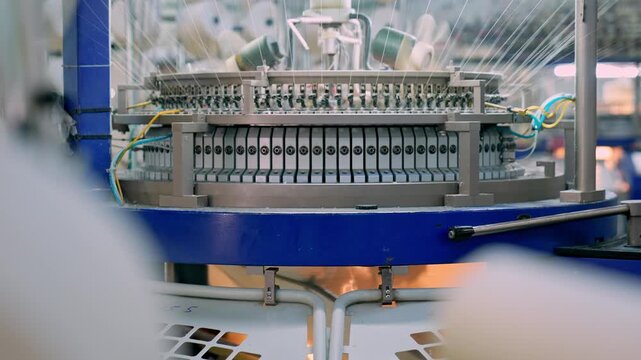 Automated circular knitting machine operating inside a modern textile factory. Professional industrial footage reflecting advanced textile technology and large scale manufacturing.