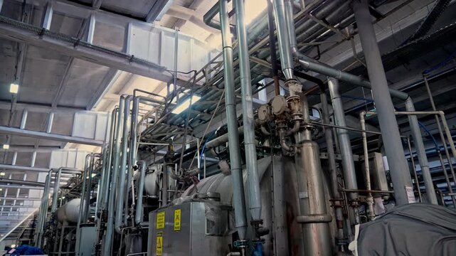 Large tanks, pipe systems and heavy machinery inside a modern textile factory. Professional industrial footage reflecting large scale manufacturing infrastructure and production technology.