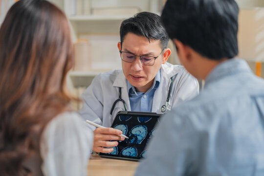 Doctor explaining brain skull MRI scan on tablet to patient during consultation at clinic highlighting neurology diagnosis medical discussion healthcare technology imaging concept professional care.