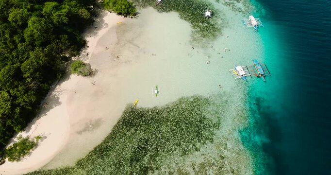 Tour boats floating over crystal clear water. Coral reefs in CYC Beach. Coron, Palawan. Philippines.