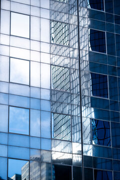 Reflections of sky on glass facade windows of modern corporate office building with urban architecture detail in business district showing clean contemporary exterior