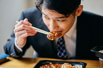 Asian businessman eating meal while working on laptop