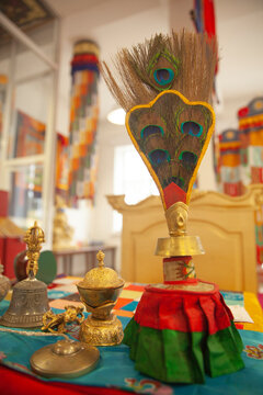 Tibetan Buddhist Ritual Vessel Bumpa with Peacock Feathers and Bell on Altar with Copy Space