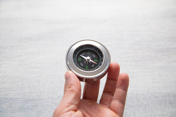 Male hand showing compass on the white table background.