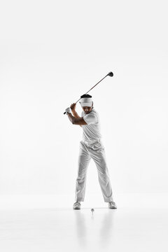 Golfer at top of backswing with driver on white studio background. Concept of powerful swing mechanics, upper body rotation control and professional golf performance training.