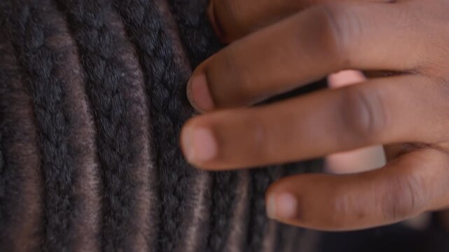Careful braid grooming. Woman carefully shaping her hair textures. Focused shot of scalp and braid adjustments. Intimate view capturing cultural hair care practices and textured scalp detail