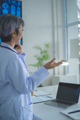 Senior Female Doctor Talking on Smartphone in Clinic Office