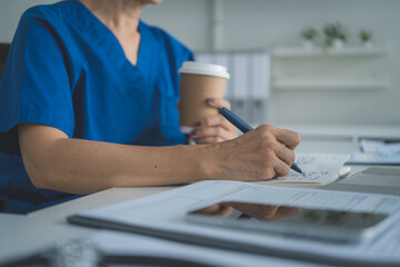 Close Up Doctor Writing Medical Notes with Coffee Cup on Desk