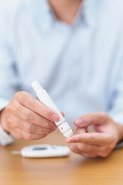 Hand using lancet pen on finger with Blood drop glucose testing or Diabetes checking by digital blood glucose meter. blood sugar level, Diabetes Day, Glycemia, Hypoglycemia, Hyperglycemia and insulin