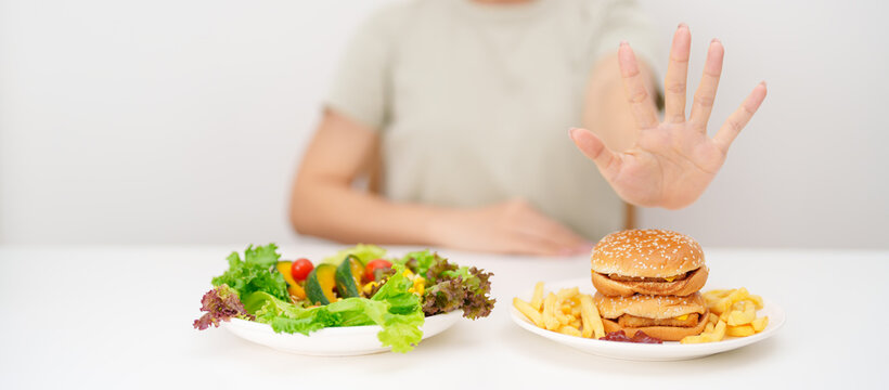 woman showing Rejecting and refusing with Hamburger. Healthy and Unhealthy Food Choice, Calories and Nutrition of vegetables Salad and Hamburger. dieting, weight loss, junk food and lifestyle