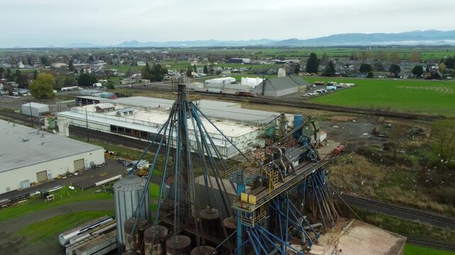 US, OR, Harrisburg, , 2025-11-23 - Drone view of birds circling a chemical processing plant with old dirty pipes leading to a tower at CHS Nutrition, in fall