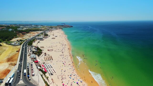 A drone pulls back over Carcavelos Beach with umbrellas and swimmers along Portugal&rsquo;s Atlantic coast