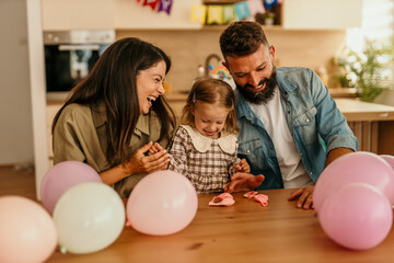 Fototapeta premium Parents celebrating child's birthday at home with balloons