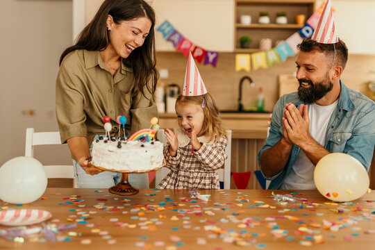 Adorable child celebrating birthday with cake and confetti at home