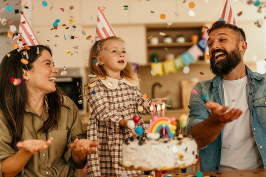 Child celebrating with adults enjoying a festive moment with cake