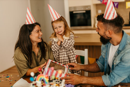 Young child receiving gift from smiling parents at home