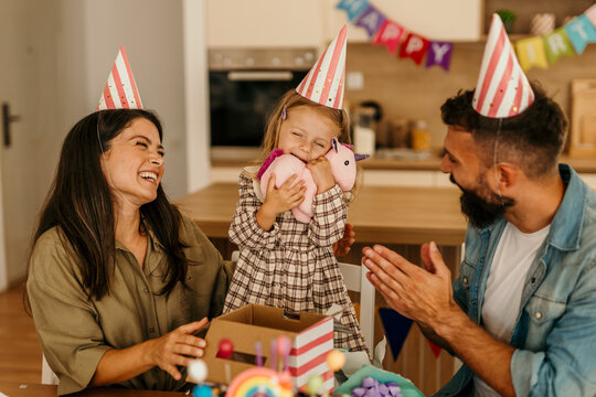Child receiving a gift embracing a unicorn toy