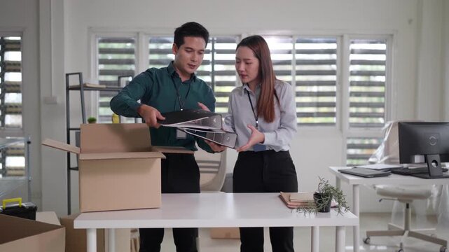 Asian adult colleagues pack unpack organize new office supplies documents for business relocation or workspace setup