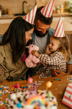 Family parents playing with daughter receiving toy unicorn