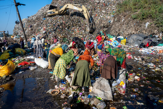 Chattogram, Bangladesh - 25 November 2025: View of people sifting through a vast, sprawling landfill, the heavy machinery looming over them, amidst the stark reality of waste and resilience.