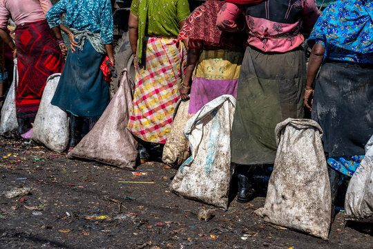 Chattogram, Bangladesh - 26 November 2025: View of women standing in a row, each carrying a large sack, vibrant fabrics contrasting with the grimy ground.