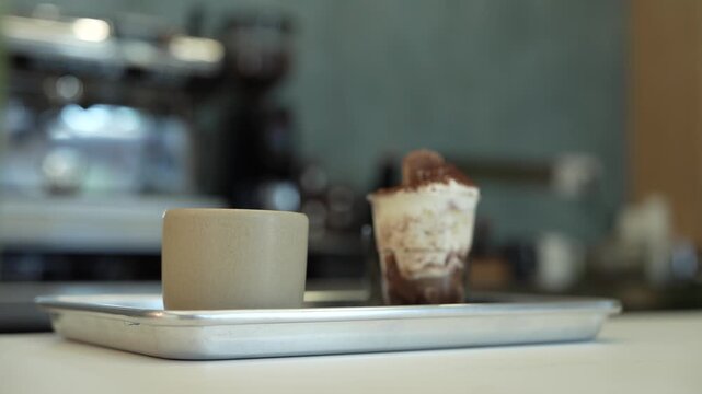 Barista placing a parfait on a metal tray before serving a customer