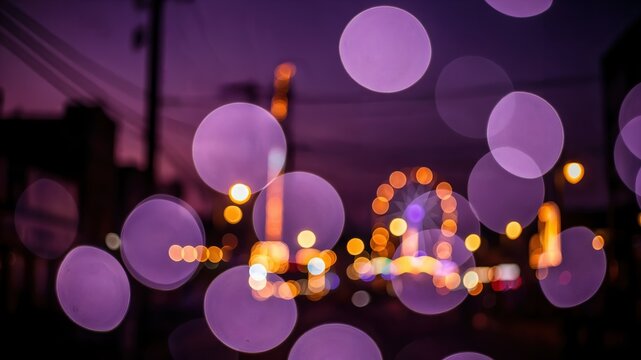 Abstract purple and orange bokeh lights of an amusement park fairground at night