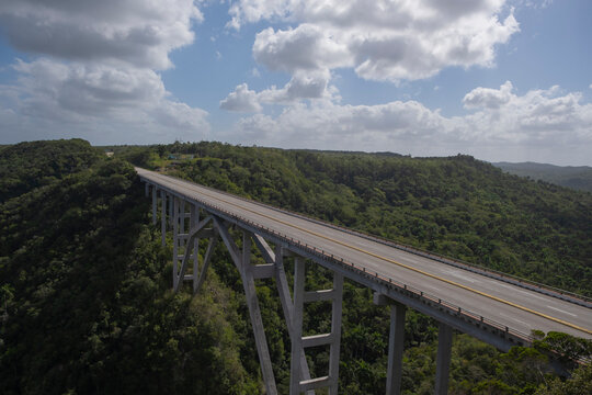 Aerial view of empty high concrete bridge and highway road trough green tropical forest and mountains over a deep canyon. Bacunayagua Bridge, Matanzas, Cuba.
