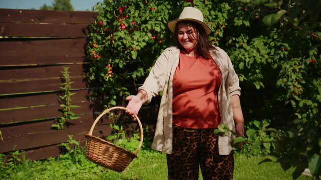 Woman Collecting Fresh Apples in a Lush Garden with Sunlight Casting Playful Shadows, Enjoying Nature and the Harvesting Experience with a Joyful Smile