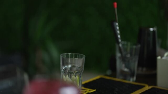 Hands crushing ingredients with muddler in cocktail glass