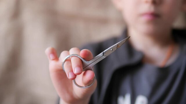 scissors in hand - Immersive POV of a boy simulating a rhythmic snipping motion with metal scissors. A close-up sensory study of a child's hand operating small steel scissors toward the camera lens