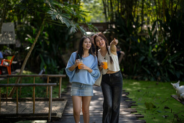Fototapeta premium Young women friends walking enjoying orange juice together