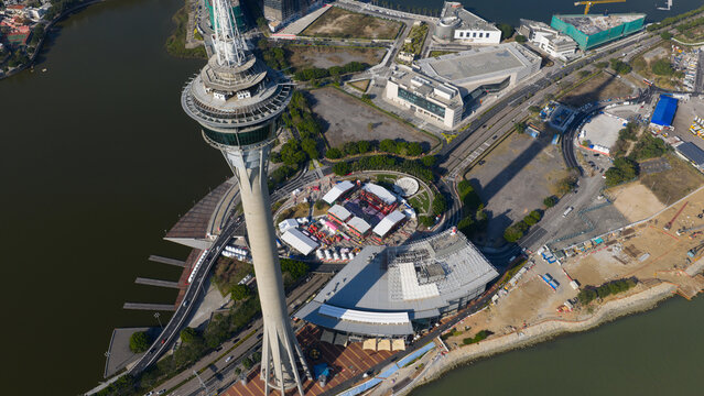 Macao, Macao - 16 February 2026: Aerial view of the towering Macau Tower piercing the sky, its sleek silhouette contrasting against the shimmering harbor waters and the vibrant cityscape below.