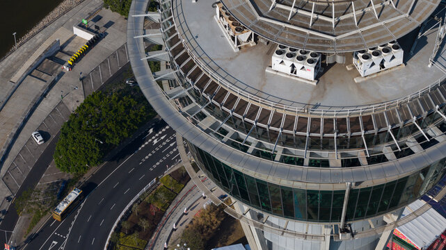 Macao, Macao - 16 February 2026: Aerial view of the city's iconic tower, its circular crown gleaming under the sun, contrasting with the winding roads below.