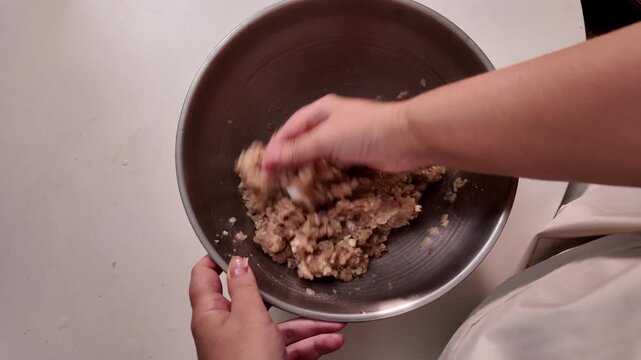 Woman mixes minced meat in a metal bowl, cooking homemade food