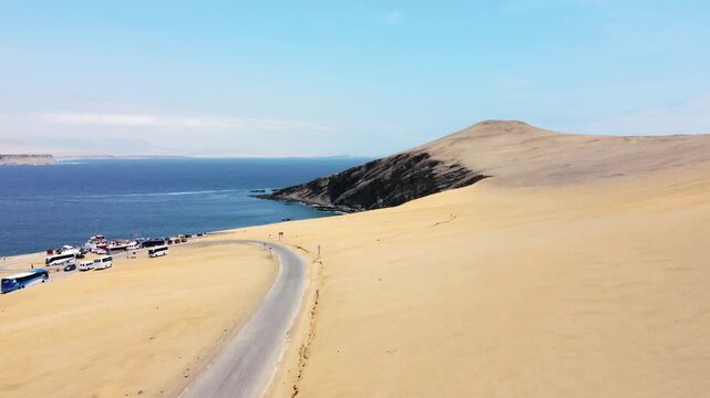 Drone aerial view, road sand beach, big waves and road in desert cliff blue sea clear sky blue parking lot. Paracas National Park, Peru 4k