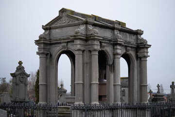 Obraz premium Large ornate stone mausoleum with classical arches and columns in a cemetery