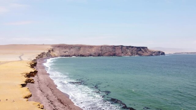 Drone aerial view, red sand beach, big waves and road in desert cliff blue sea clear sky blue. Paracas National Park, Peru 4k